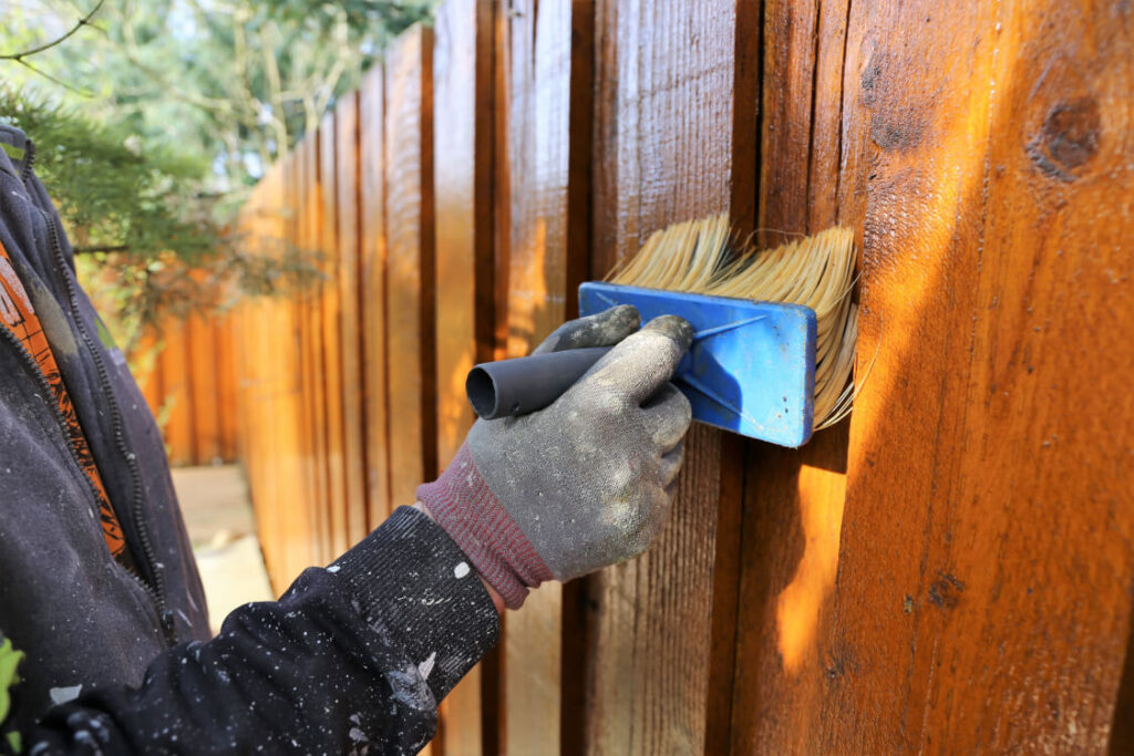 painting fence with brush
